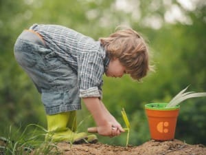 A picture of a child digging into the ground with spade.