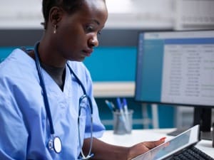 A picture of a female Healthcare worker on an electronic device.