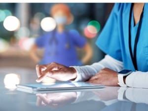 An image with a healthcare worker on an iPad with a System C healthcare character in the background.