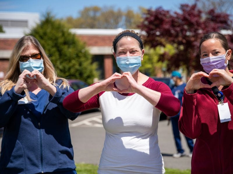A picture of three nurses with their hands in a heart shape.