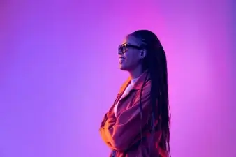 A woman smiling with a purple background.