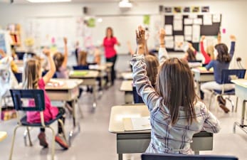 A classroom with children raising there hands