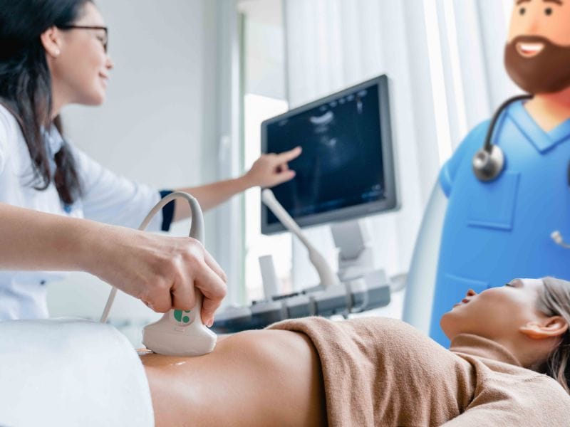 A picture of a consultant scanning a woman's stomach during early pregnancy, in a hospital setting.